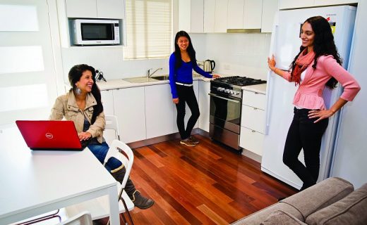 Tři studentky stojí společně v kuchyňi