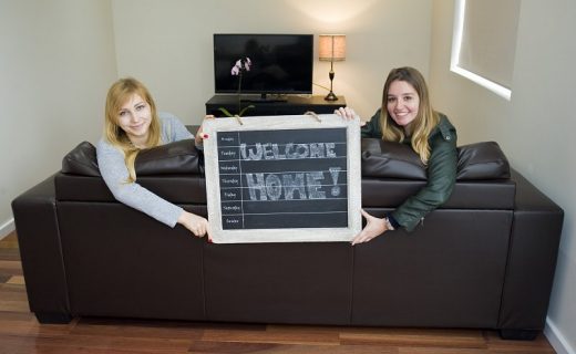 Dvě dívky drží ceduli Welcome Home